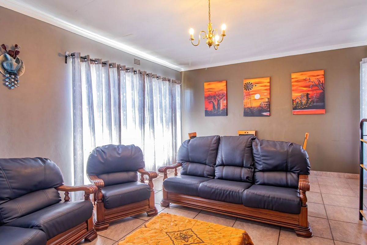 A well-lit living room featuring neutral wall tones, tiled flooring, and a classic ceiling light fixture.
