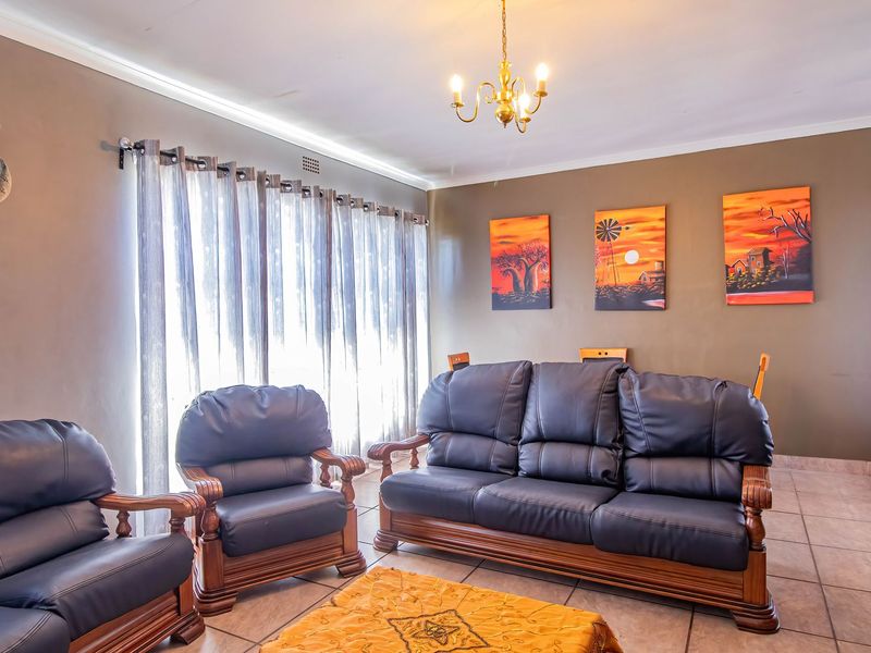 A well-lit living room featuring neutral wall tones, tiled flooring, and a classic ceiling light fixture.
