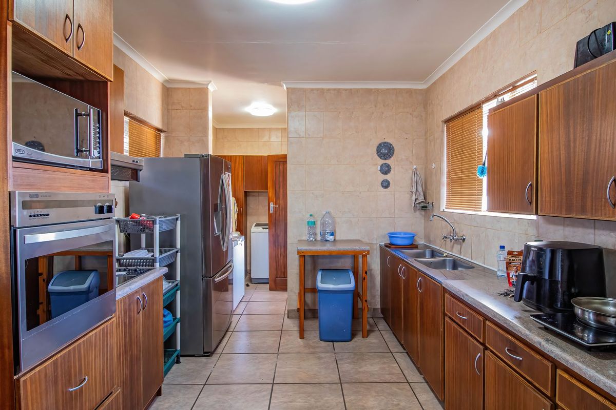 A functional kitchen featuring wood-finish cabinetry, built-in oven and microwave, double sink, and tiled surfaces throughout.