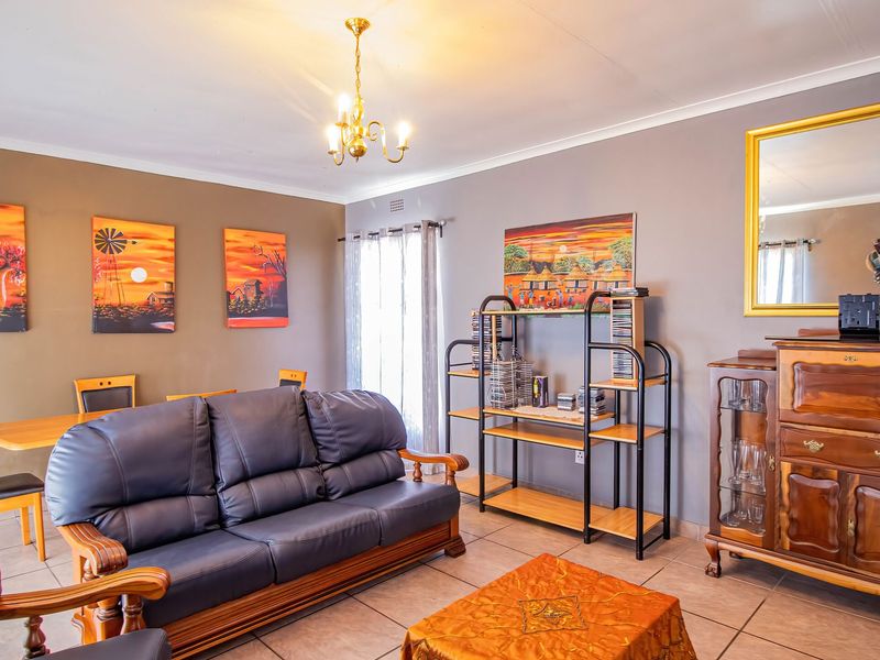 A spacious living room featuring neutral wall tones, tiled flooring, and a classic ceiling light fixture, offering a comfortable and functional living space.