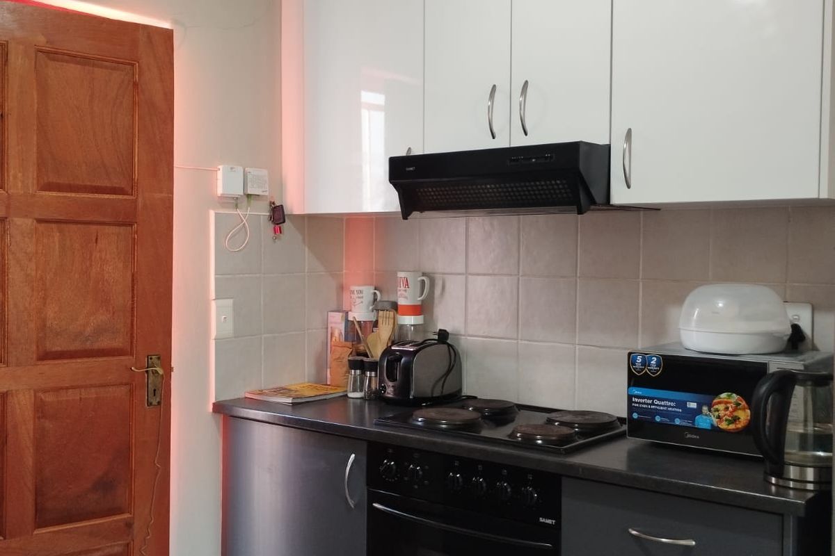 A functional kitchen featuring modern two-tone cabinetry, a built-in oven with electric hob, extractor fan, and tiled backsplash.