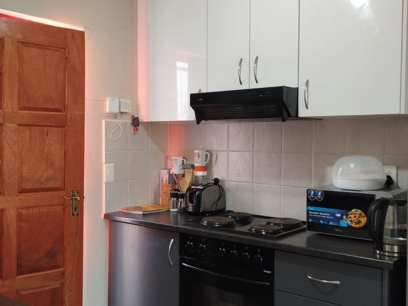A functional kitchen featuring modern two-tone cabinetry, a built-in oven with electric hob, extractor fan, and tiled backsplash.