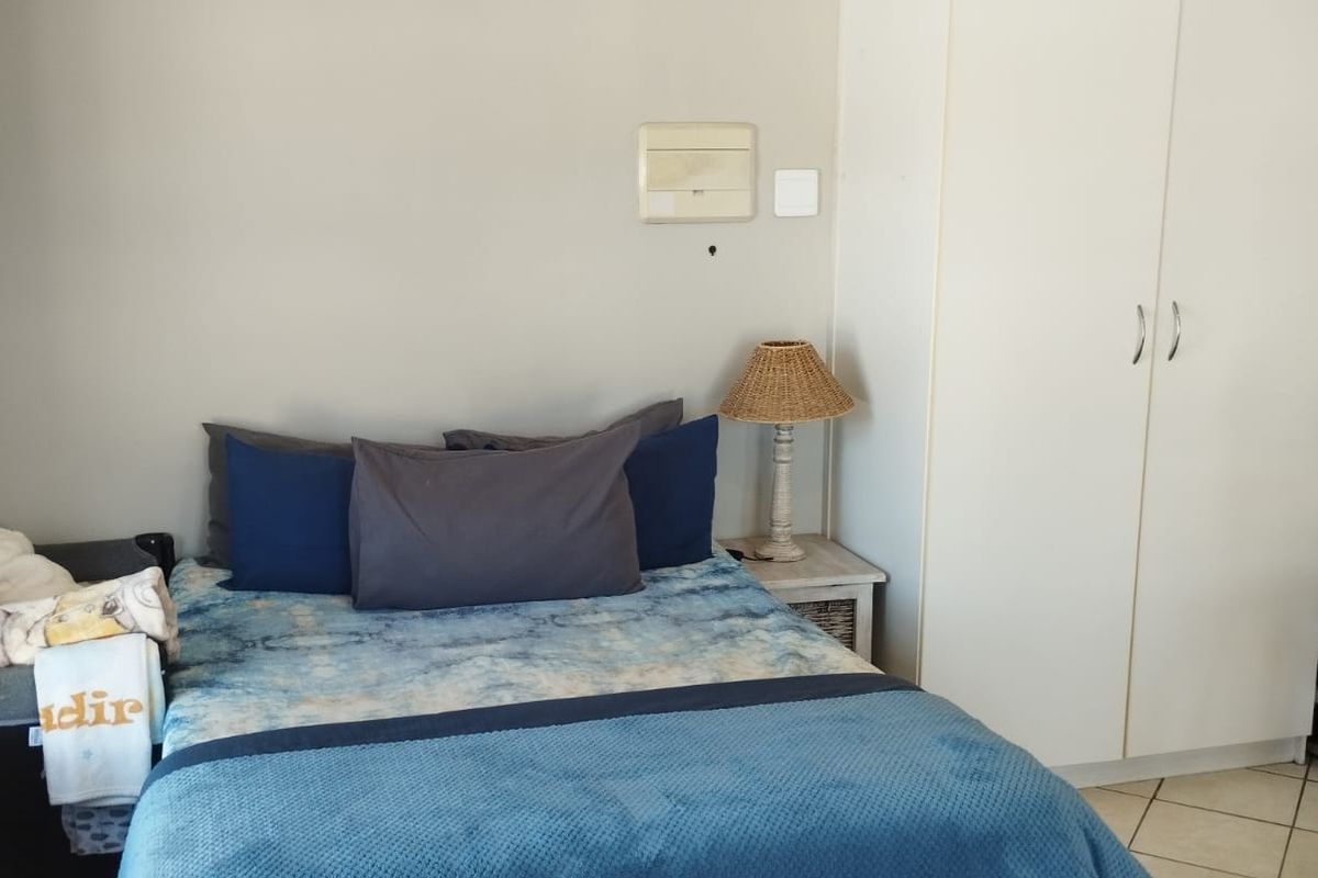 A functional bedroom featuring tiled flooring, a built-in white wardrobe, and neutral wall finishes, providing a clean and practical living space.