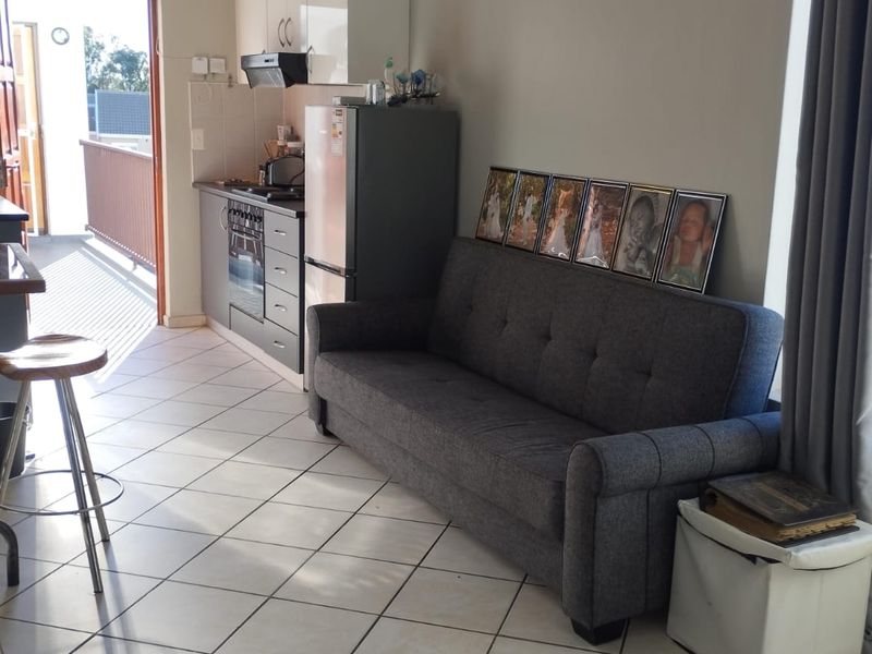 Open-plan living area featuring a compact kitchen with built-in cabinetry and direct access to a private balcony.