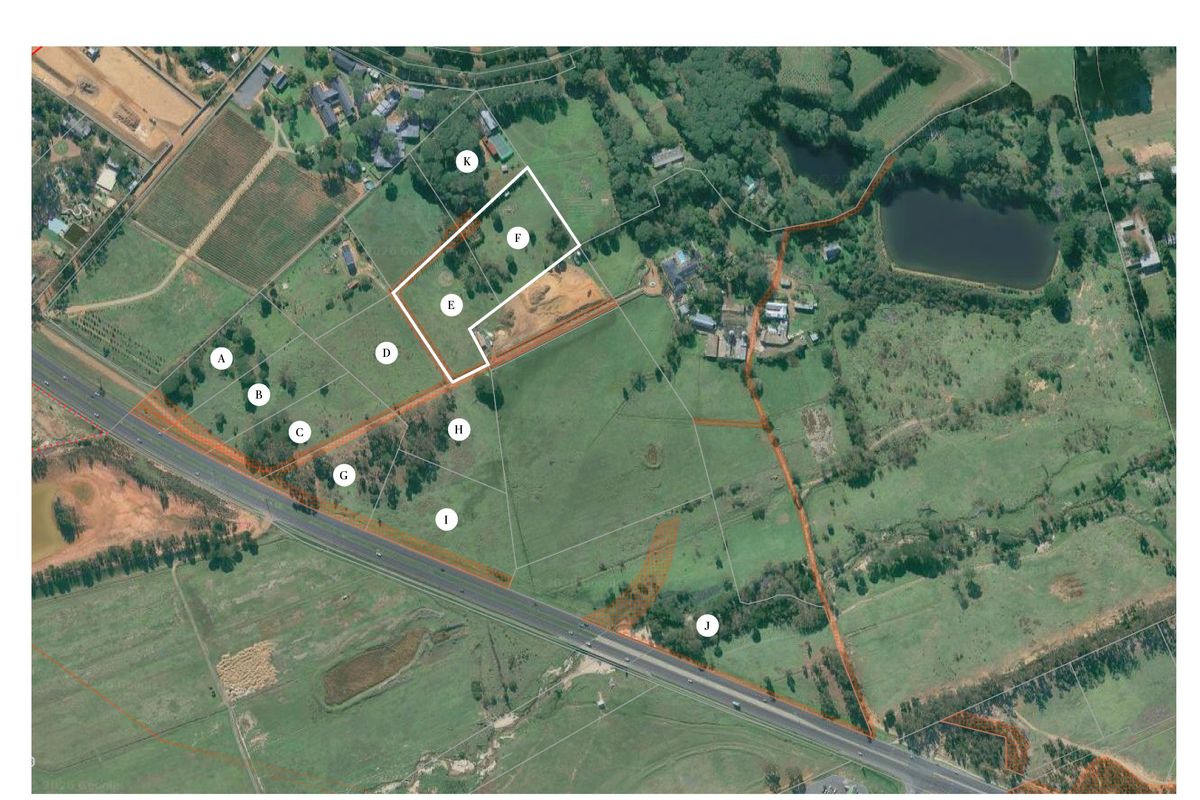 Aerial view of a large vacant residential land parcel with marked boundaries and surrounding landscape features.