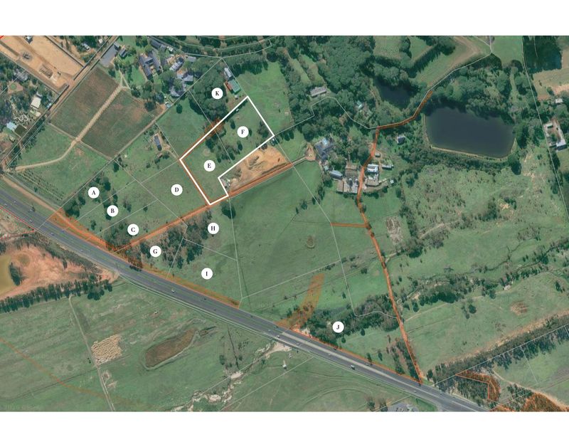 Aerial view of a large vacant residential land parcel with marked boundaries and surrounding landscape features.