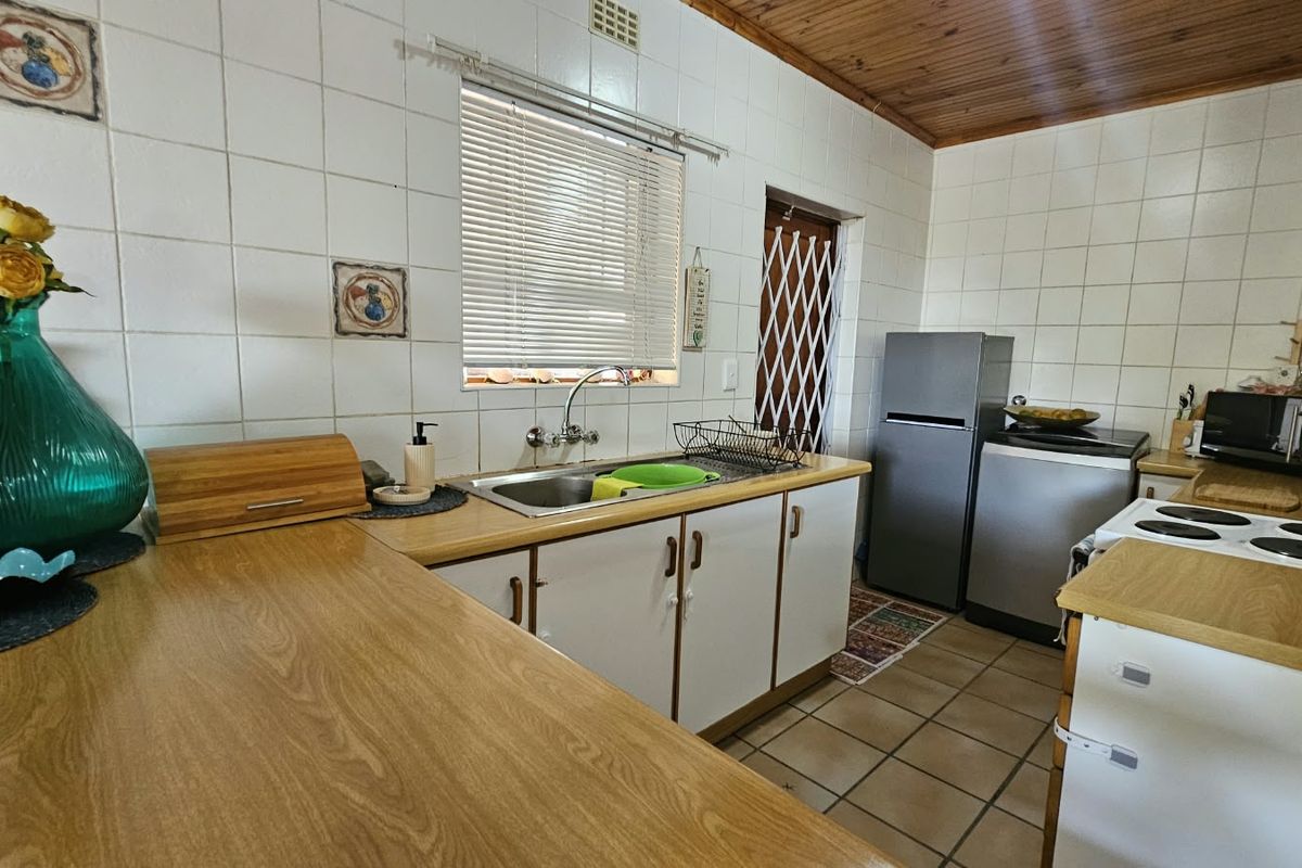 A functional kitchen featuring laminate countertops, tiled backsplash, and timber ceiling, offering a dated aesthetic with potential for modern renovation.