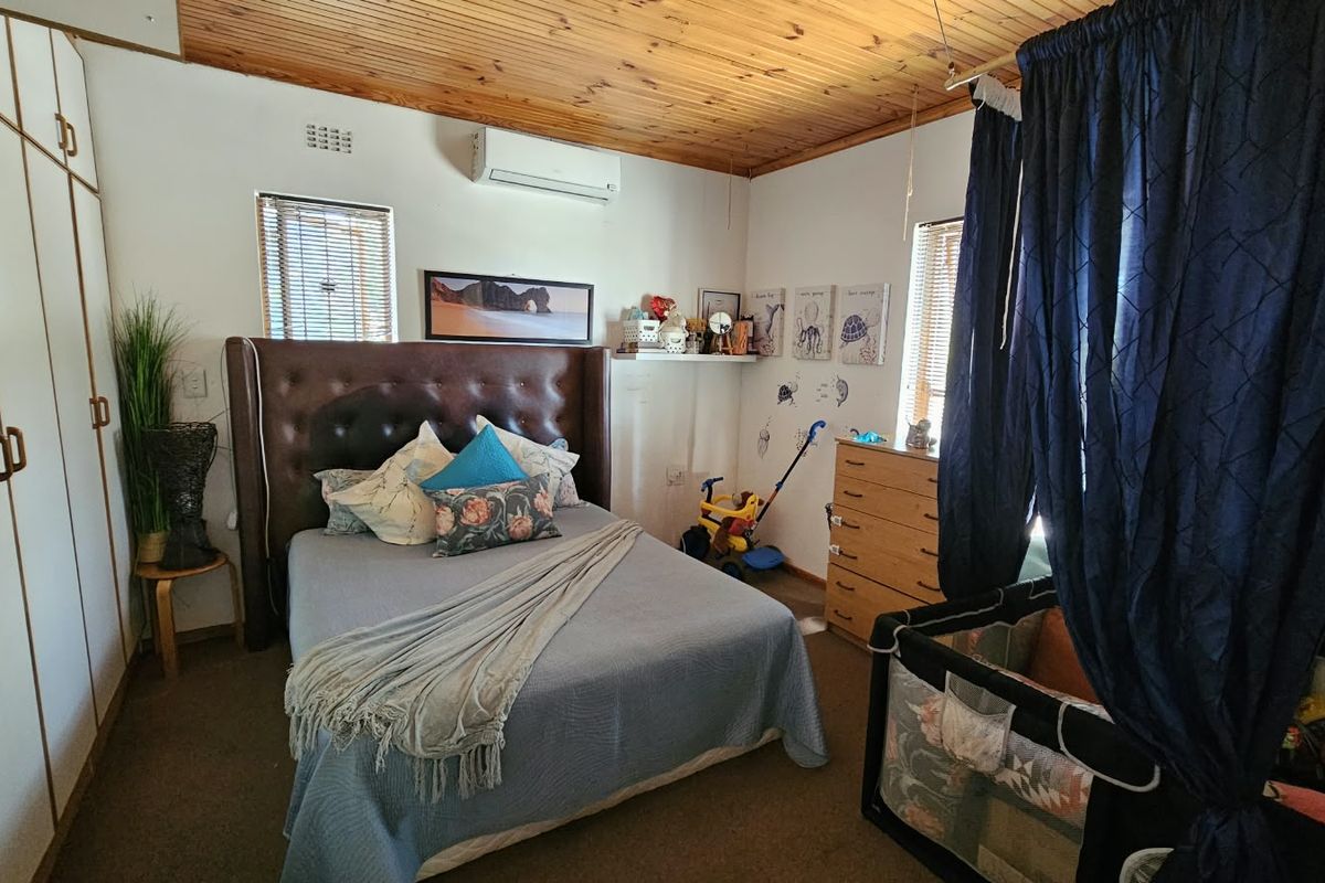 A bedroom featuring built-in cupboards, a timber-paneled ceiling, and a wall-mounted air conditioning unit.
