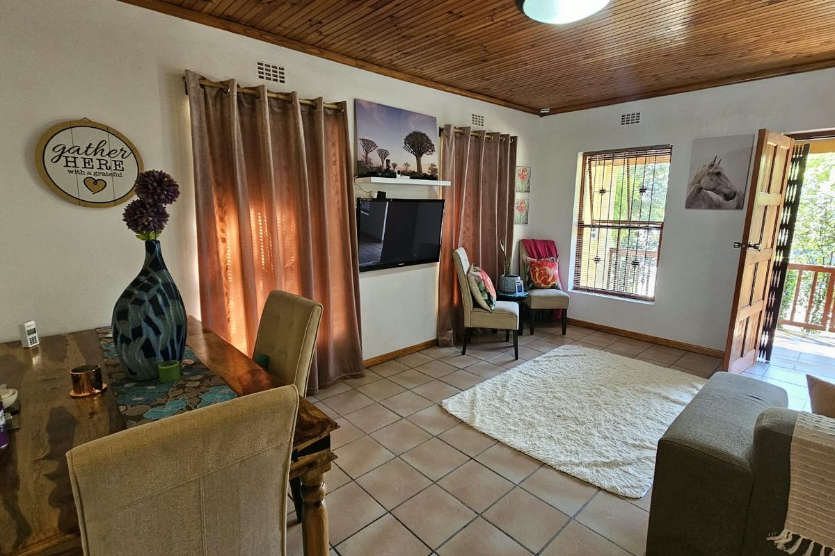 A living room featuring tiled flooring and a timber ceiling, with direct access to an outdoor patio area through a wooden door.