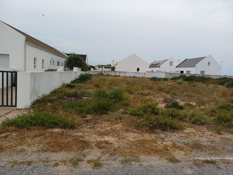A vacant residential plot featuring a boundary wall and gated entrance, situated within a developed neighborhood.
