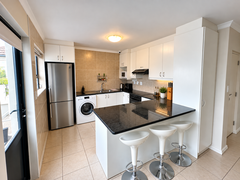 Modern kitchen featuring granite countertops, a breakfast bar, built-in appliances, tiled backsplash, and ample cabinetry, offering a clean and functional cooking space.