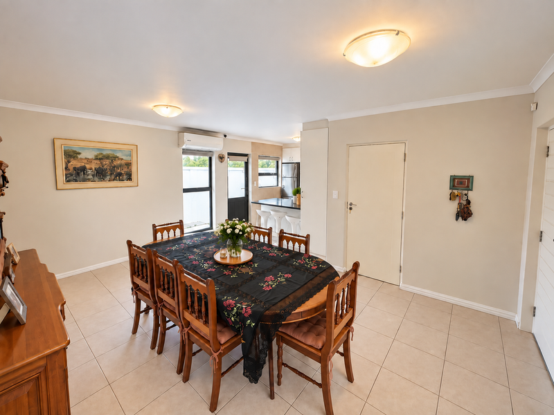 An open-plan dining area featuring tiled flooring, neutral walls, and a seamless transition into the adjacent kitchen space.