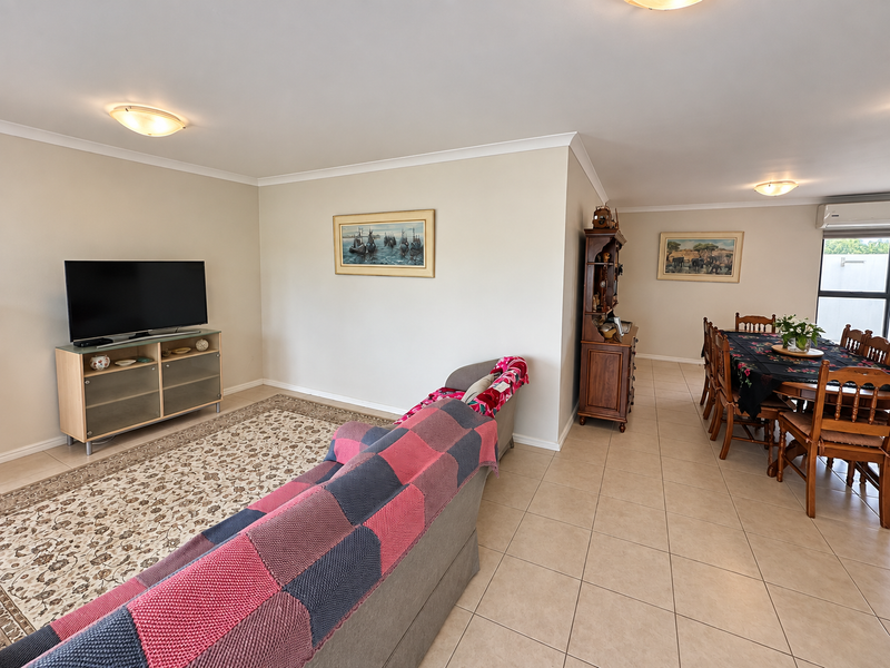 Spacious open-plan living and dining area featuring neutral wall tones, tiled flooring, and an integrated air conditioning unit.