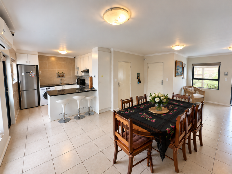 An open-plan living and dining area featuring a functional kitchen with granite countertops, tiled flooring, and integrated cabinetry.