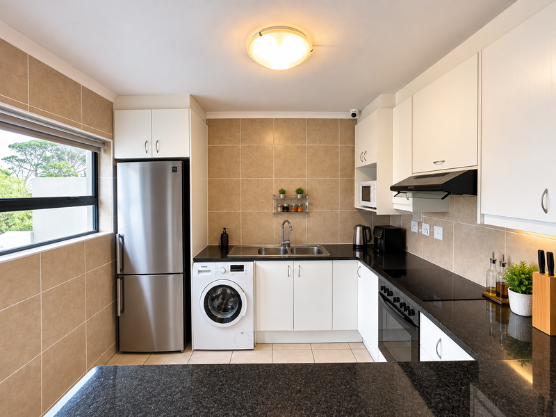 A well-maintained kitchen featuring granite countertops, white cabinetry, a built-in oven, electric cooktop, and an integrated washing machine.