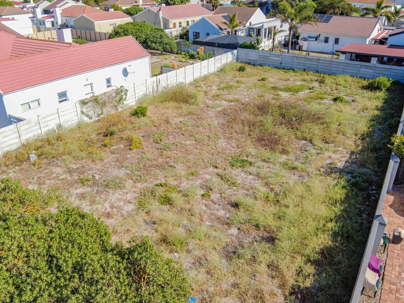 An elevated aerial view of a vacant residential plot enclosed by precast concrete boundary walls in a developed suburban neighborhood.