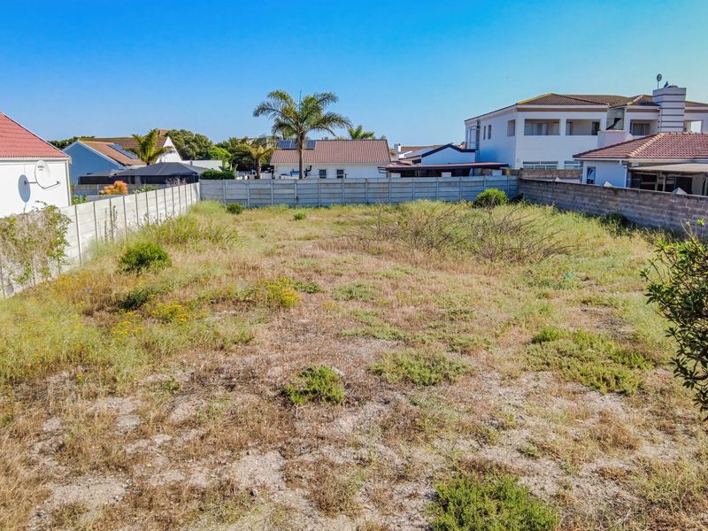A vacant residential plot featuring a level surface enclosed by precast concrete boundary walls, situated within an established residential neighborhood.