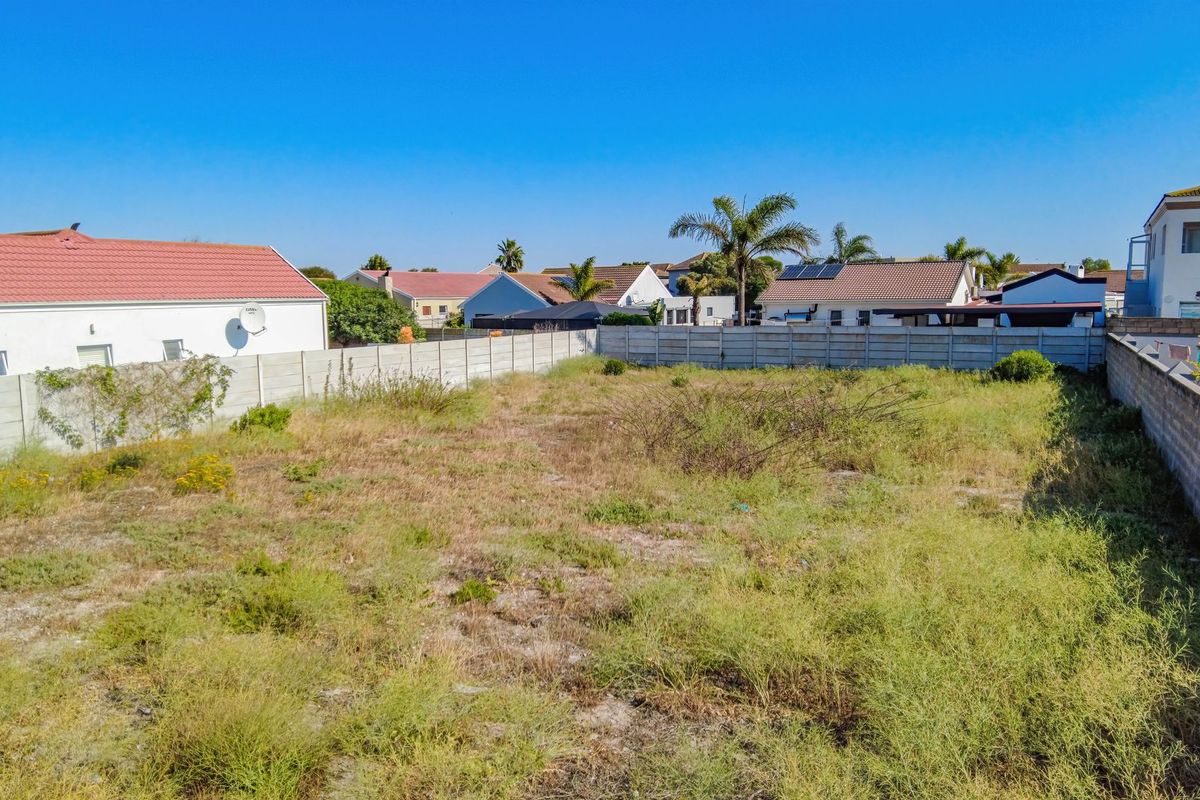 A vacant residential plot enclosed by precast concrete boundary walls, situated in a developed suburban neighborhood.