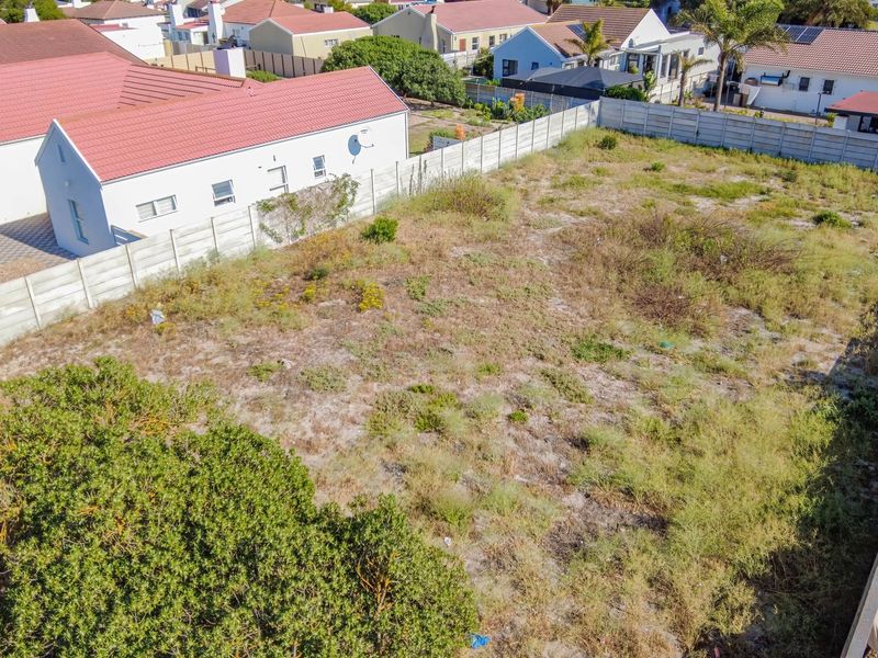 An aerial view of a vacant residential plot enclosed by precast concrete boundary walls, situated within an established suburban neighborhood.