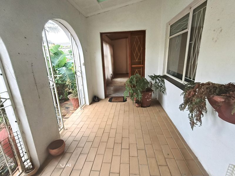 A covered patio area featuring tiled flooring, an arched entrance, and security features, providing a transition space into the home interior.