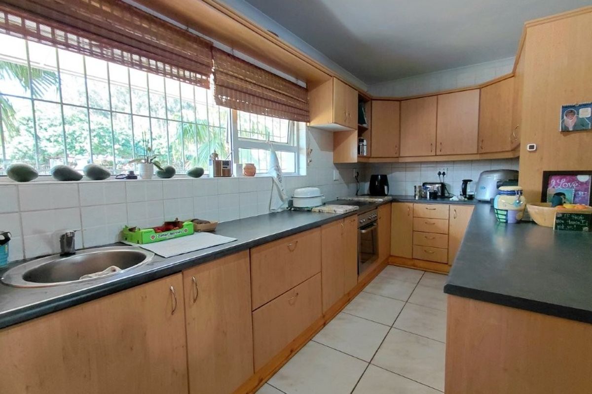 Functional kitchen featuring laminate cabinetry, tiled backsplash, built-in oven, and ample counter space with a large window overlooking the exterior.