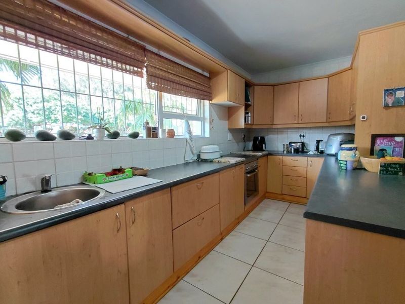 Functional kitchen featuring laminate cabinetry, tiled backsplash, built-in oven, and ample counter space with a large window overlooking the exterior.
