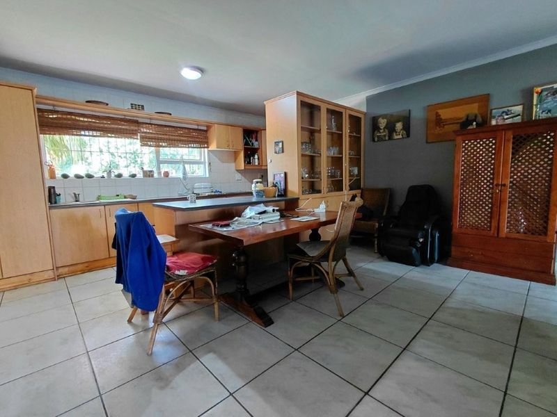 Open plan kitchen and dining area featuring tiled flooring, wooden cabinetry, and a breakfast bar, offering a functional layout for daily living.
