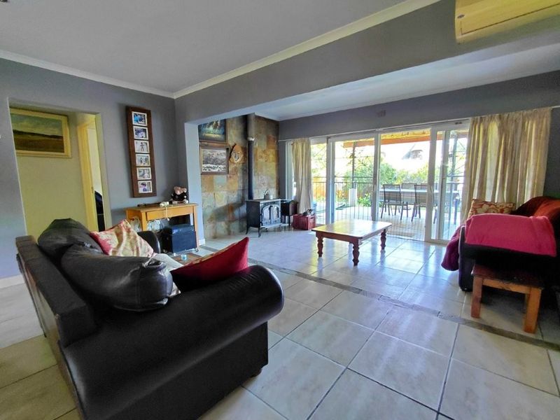 Spacious living room featuring tiled flooring, a stone feature wall with a freestanding fireplace, and large sliding glass doors leading to the patio.