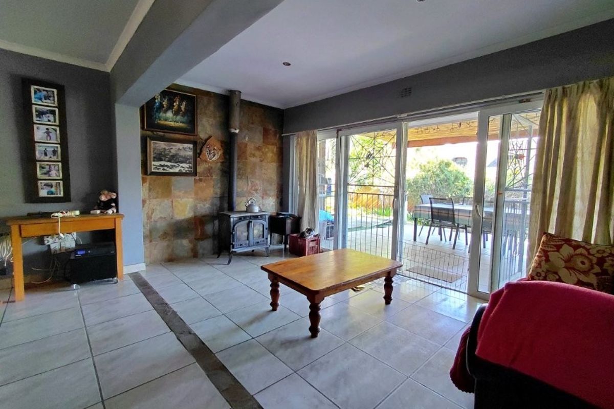 Spacious living room featuring tiled flooring, a stone feature wall with a built-in fireplace, and large sliding glass doors leading to the patio.