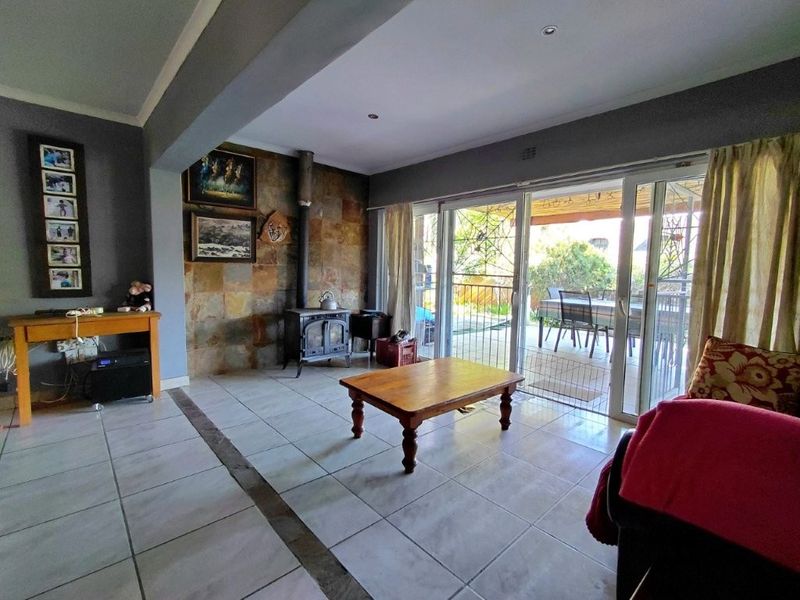 Spacious living room featuring tiled flooring, a stone feature wall with a built-in fireplace, and large sliding glass doors leading to the patio.