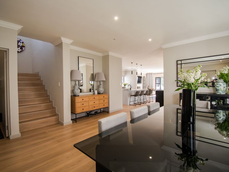 Spacious open-plan living area featuring engineered timber flooring, a modern kitchen island, and a timber staircase leading to the upper level.