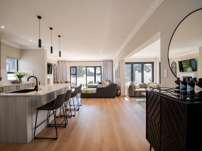 Spacious open-plan living area featuring a modern kitchen with a large island, stone countertops, and seamless flow to the lounge and outdoor patio.