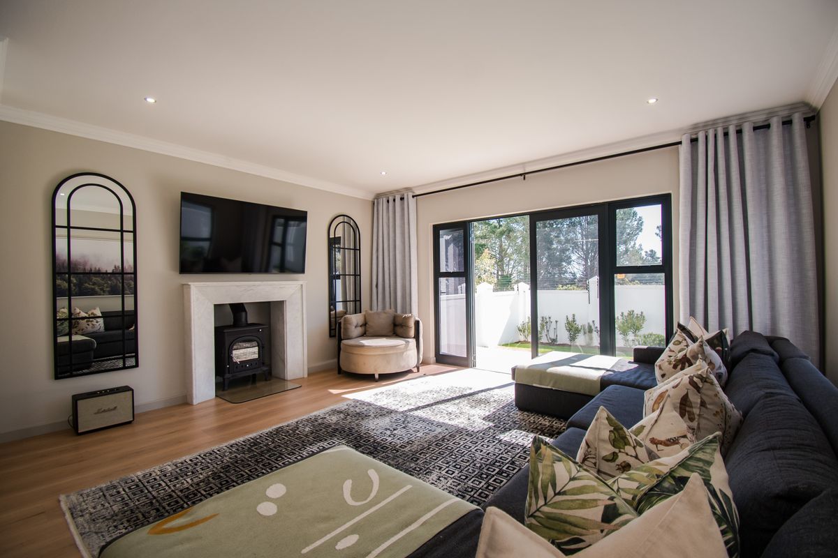 A bright and modern living room featuring a fireplace with a wood-burning stove, laminate flooring, and large sliding doors leading to the garden.