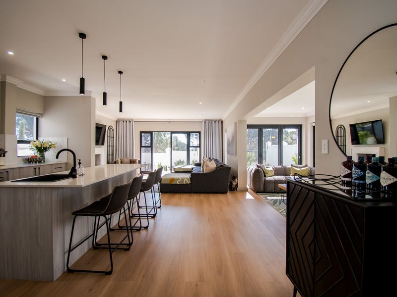 Spacious open-plan living area featuring a modern kitchen with a large island, stone countertops, and seamless flow to the lounge and outdoor patio.
