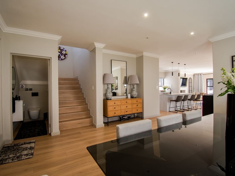 Spacious open-plan living area featuring modern timber flooring, a sleek kitchen island with pendant lighting, and a convenient ground-floor guest bathroom.