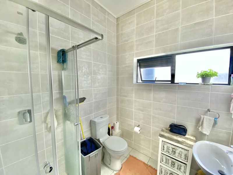A modern bathroom featuring a walk-in shower with a glass enclosure, tiled walls, and a wall-mounted basin.