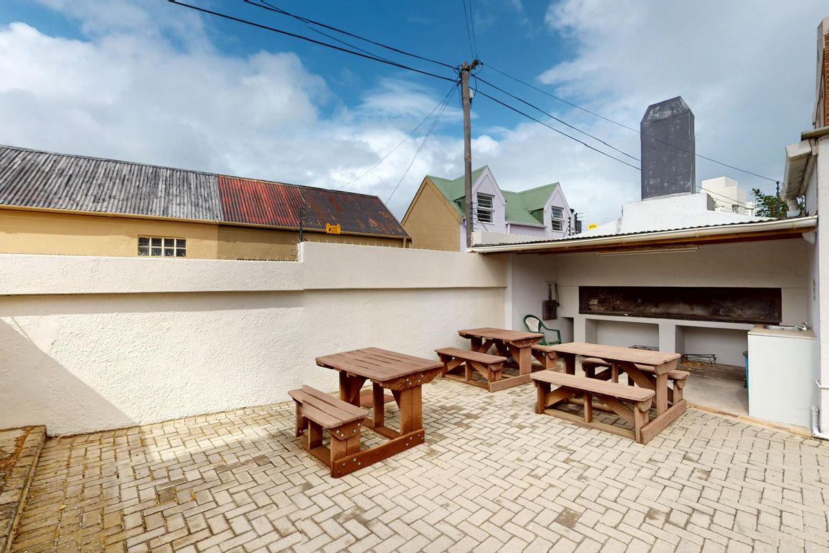 Rear courtyard featuring a paved patio area and a built-in braai facility with a chimney.