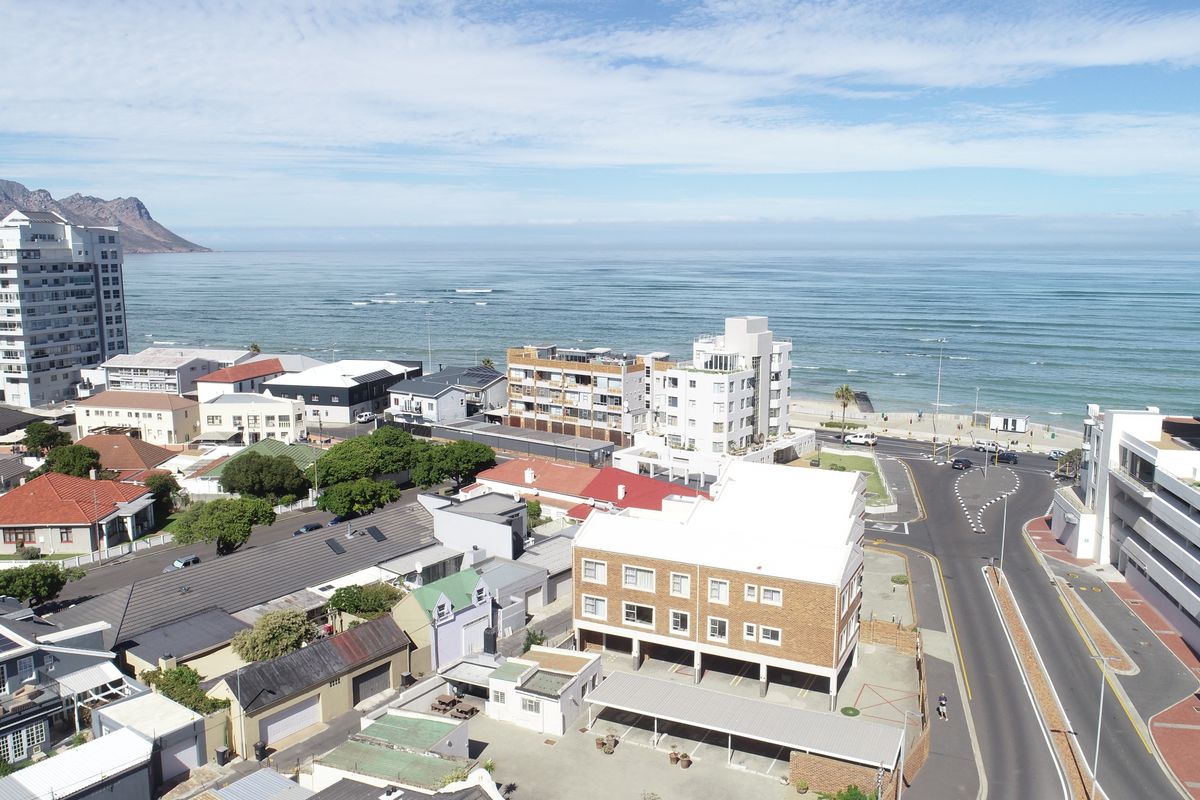 An aerial view of the coastal apartment complex and surrounding urban neighborhood, showcasing proximity to the beach and local infrastructure.