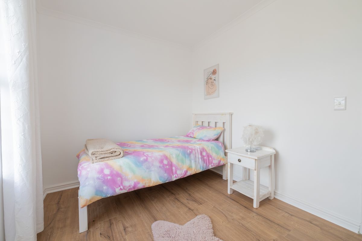 A bright and clean bedroom featuring modern laminate flooring and neutral white walls, providing a versatile space for personalization.