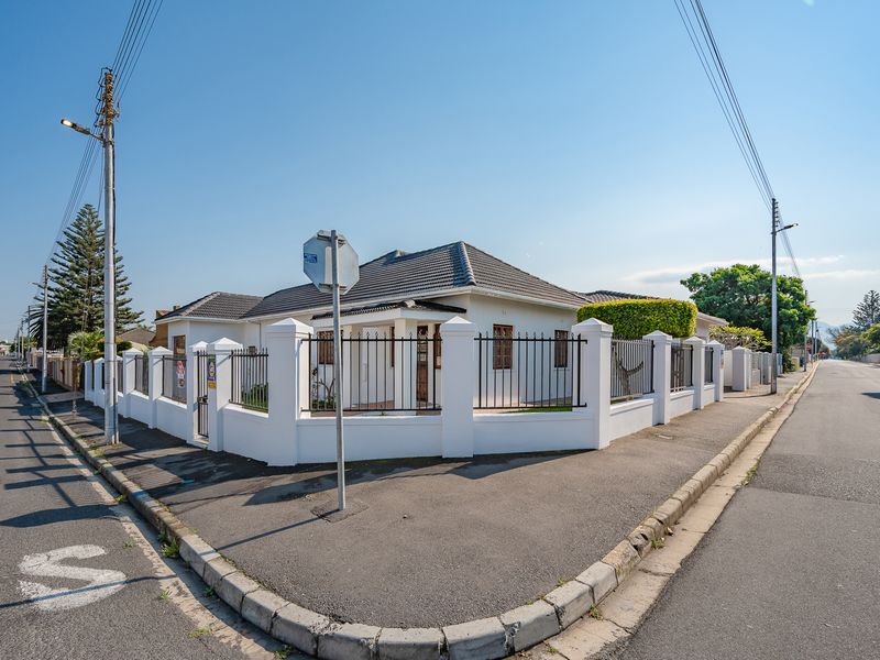 Corner property featuring a well-maintained white perimeter wall with wrought iron fencing and a classic tiled roof structure.