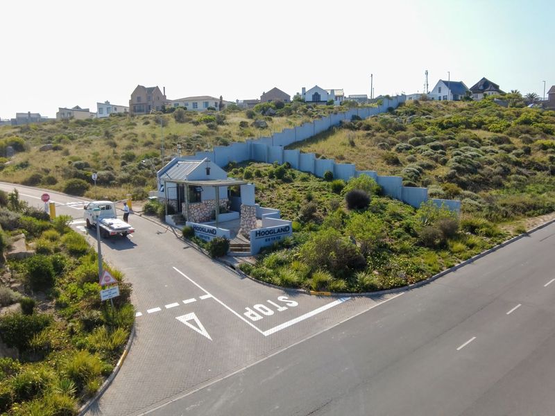 Aerial view of the Hoogland Estate entrance, featuring a security gatehouse, perimeter walling, and paved access road.