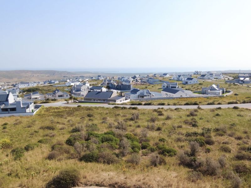 An aerial view of a residential estate featuring established homes, paved roads, and surrounding natural landscape.