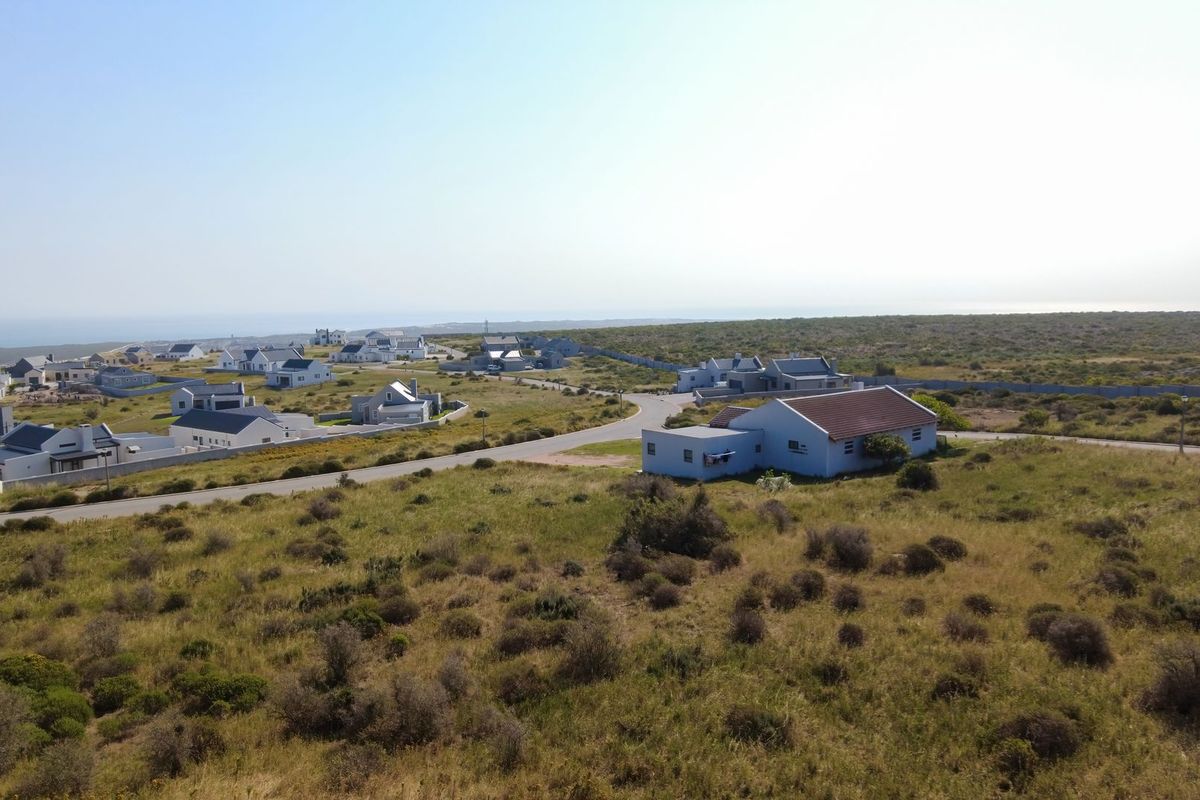 An aerial view of a residential coastal estate featuring paved roads and surrounding natural landscape.