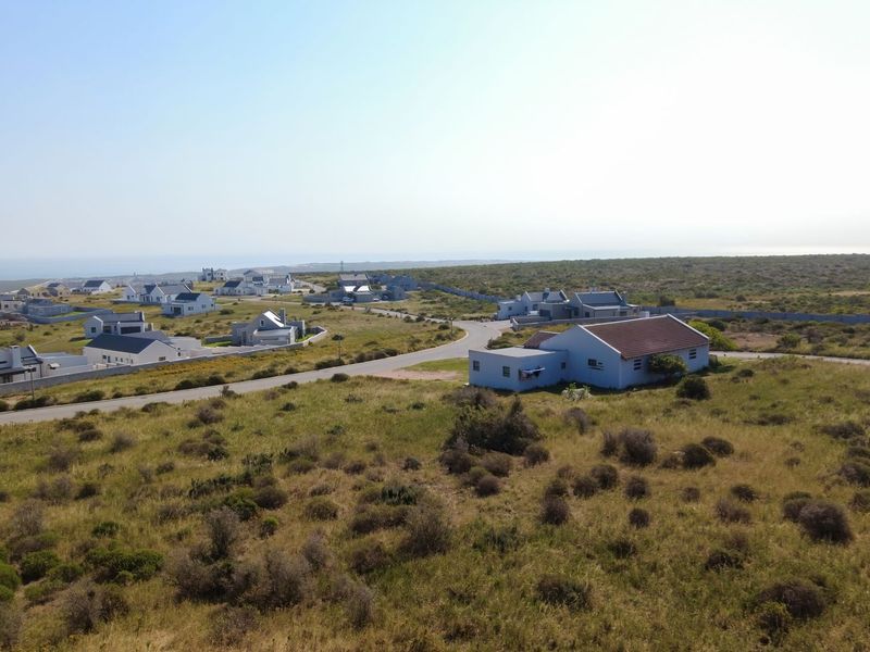 An aerial view of a residential coastal estate featuring paved roads and surrounding natural landscape.