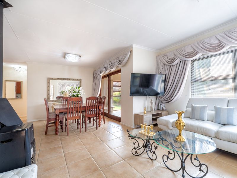 Spacious open-plan living and dining area featuring ceramic tile flooring, a freestanding fireplace, and direct access to the outdoor patio through sliding glass doors.