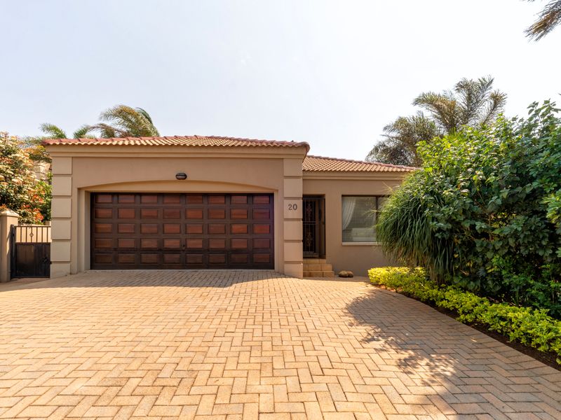 Front elevation of a townhouse featuring a paved driveway, a wooden double garage door, and a secure entrance with a tiled roof.