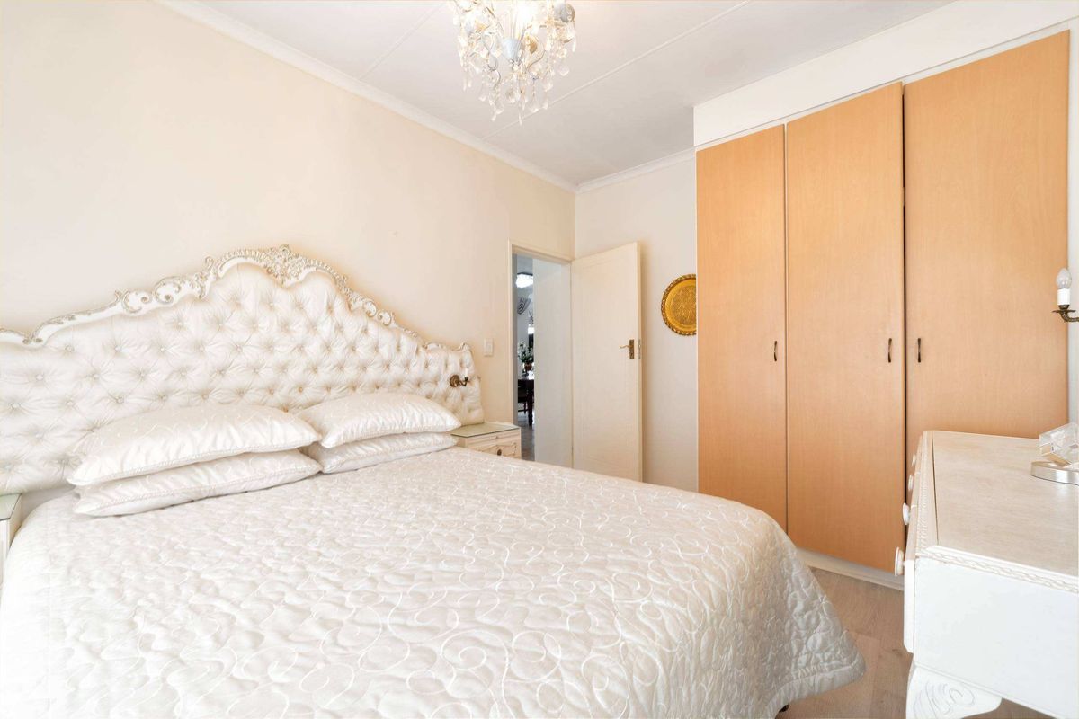 A well-lit bedroom featuring built-in wooden cupboards and classic coving, offering a comfortable and functional living space.