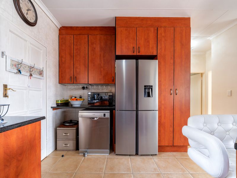 A functional kitchen area featuring wood-finish cabinetry, tiled flooring, and dedicated space for appliances, offering a practical layout for daily use.