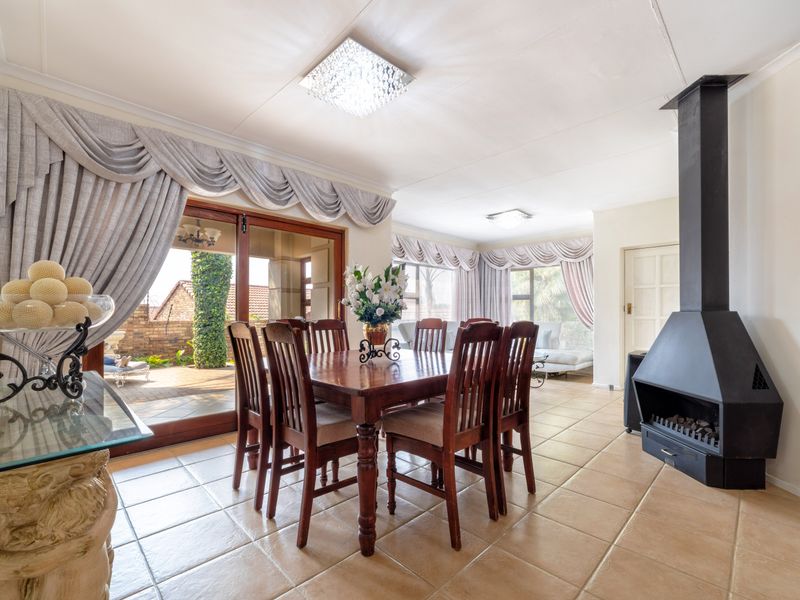 Spacious open-plan dining and living area featuring tiled flooring, a prominent black freestanding fireplace, and large sliding doors leading to the patio.