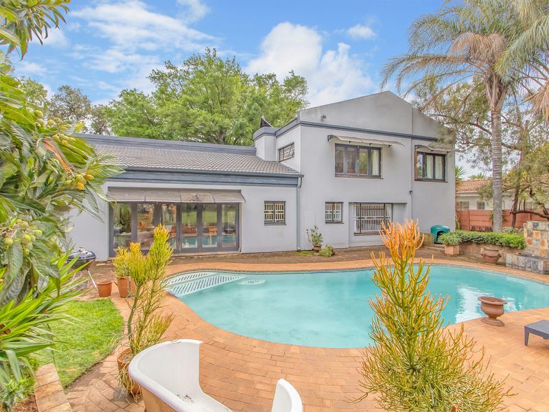 Rear view of the house featuring a swimming pool, brick paved patio area, and sliding glass doors leading into the living space.